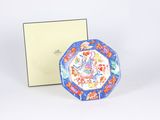 a blue and red plate sitting next to a white box