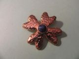 a close up of a flower brooch with a blue stone in the center