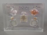 three bottles of perfume in a clear box on a table