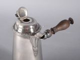 a silver coffee pot with a wooden handle on a table