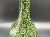 a green vase sitting on a table with a tag on it