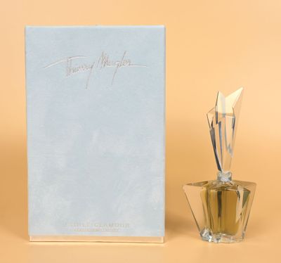 perfume bottle next to a box of perfume on a beige surface
