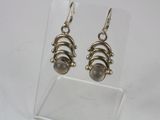 a pair of silver earrings on a clear acrylic stand