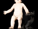 a small statue of a baby standing on a rock