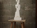 a white sculpture sitting on a wooden table in front of a brick wall