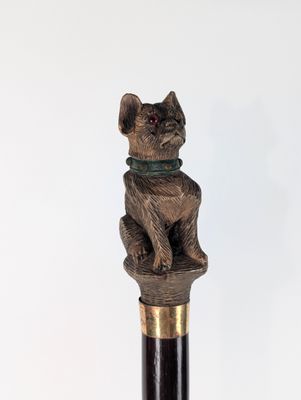 une statue représentant un chat assis sur une canne
