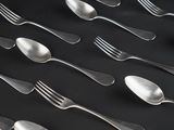 a lot of spoons and forks on a black table