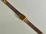 a close up of a gold watch on a white surface