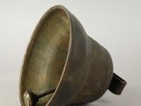 a small bronze bell on a white surface