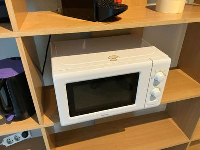 a microwave sitting on a shelf in the corner of a room