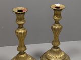 trois bougeoirs en laiton posés sur une table blanche, sur fond gris
