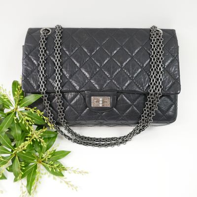 a black chanel bag with a chain strap and a flower