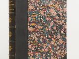 an old book with a floral design on it sitting on a table