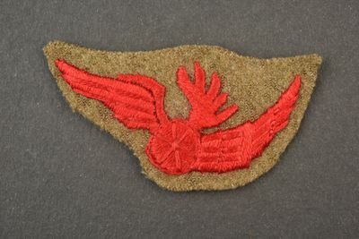 un écusson brodé représentant un oiseau rouge sur un fond gris
