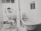 photographie en noir et blanc d'une femme nue assise sur une chaise devant une baignoire