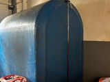 a large blue tank sitting next to a bunch of orange barrels
