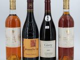 four bottles of wine are lined up on a white surface
