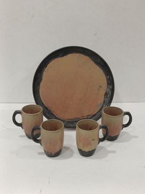 trois tasses à café et une assiette posées sur une surface blanche
