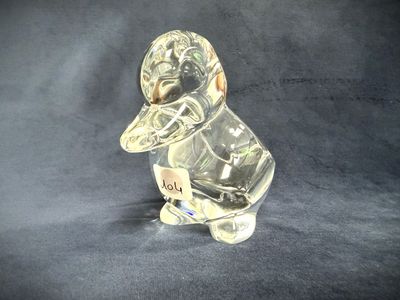 a clear glass duck with a baseball cap on it ' s head