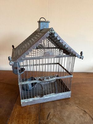 une cage à oiseaux avec un oiseau à l'intérieur, posée sur une table en bois