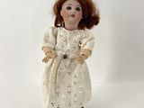 poupée en porcelaine représentant une femme aux cheveux roux vêtue d'une robe blanche