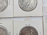four different types of coins are in a white box on a table