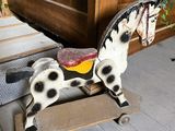 un cheval en bois posé sur une charrette en bois
