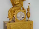 a gold clock with an angel sitting on top of it