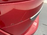 a close up of a red car with a broken door handle