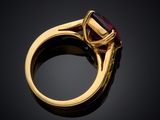 a close up of a gold ring with a red stone