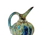 un vase bleu et vert muni d'une anse, posé sur une surface blanche