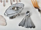 a silver plate with spoons, forks and spoons on a table