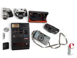 many different types of cameras and accessories laid out on a white surface