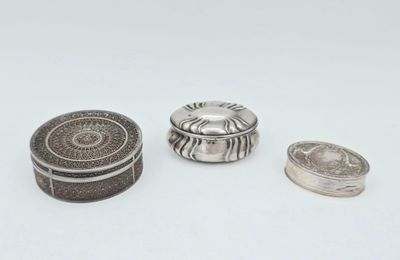 trois bijoux en argent posés sur une surface blanche, sur fond blanc