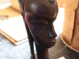 une sculpture en bois représentant la tête d'une femme, posée sur une table