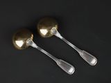 two silver spoons and a fork on a black surface