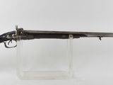 un vieux fusil au canon en bois, posé sur un socle transparent
