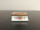 une petite boîte blanche décorée de fleurs, posée sur une table