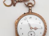 une montre de poche en or à laquelle est accrochée une clé sur le côté