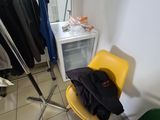 a yellow chair sitting in front of a rack of clothes