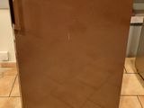 a small brown refrigerator in a kitchen with a cat sitting on the floor