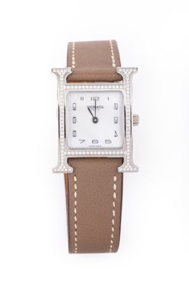gros plan d'une montre sur une surface blanche avec un bracelet marron