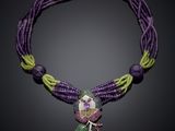 a close up of a purple necklace with green and purple beads