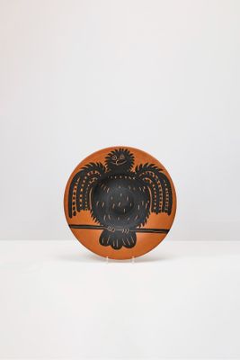 une assiette orange et noire ornée d'un motif représentant un hibou