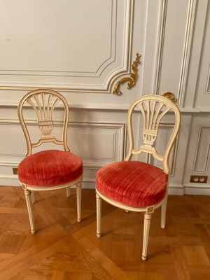 pair of chairs with red velvet upholstered seats in a white room