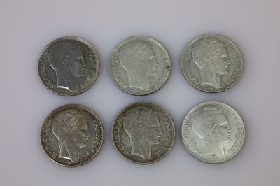 six pièces de monnaie britanniques différentes empilées les unes sur les autres sur une surface blanche