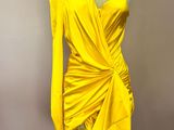 a yellow dress on a mannequin stand against a wall