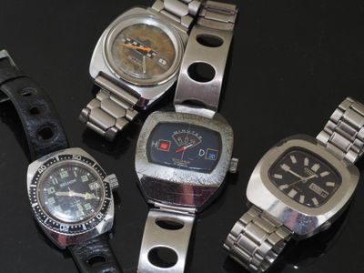 several watches are sitting on a black surface with a black background