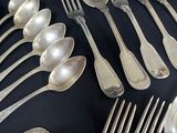 a lot of silver spoons and forks on a table