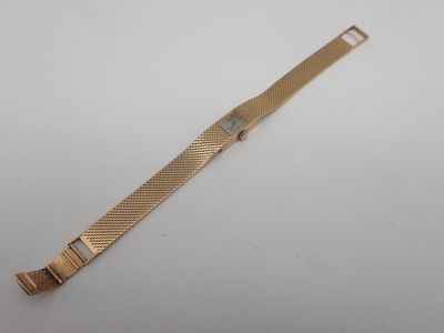 gros plan d'une montre en or sur une surface blanche